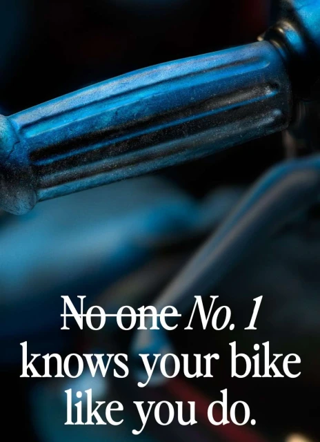 Close-up of a blue and black motorcycle handlebar with a marketing message about bike knowledge. Automotive product shot.